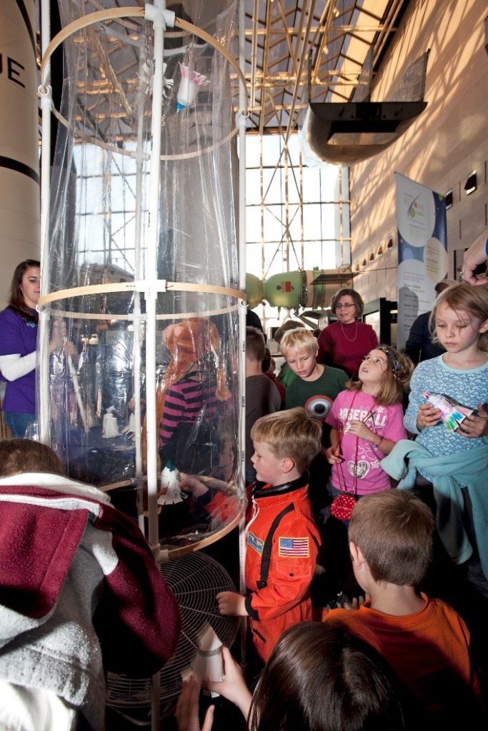 Visitors to the Spark!Lab use a wind tunnel invention. 